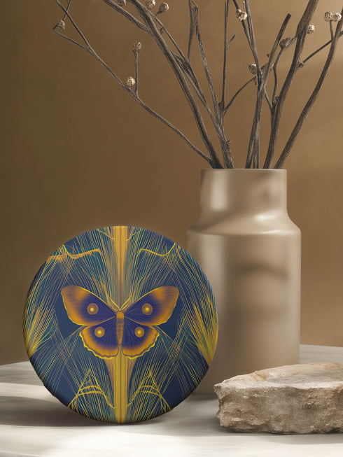 Round ceramic coaster featuring golden Luna moth illustration on dark green background with rose gold linear patterns. Cork-backed, 4-inch diameter. Perfect for vintage nature and gothic decor enthusiasts.